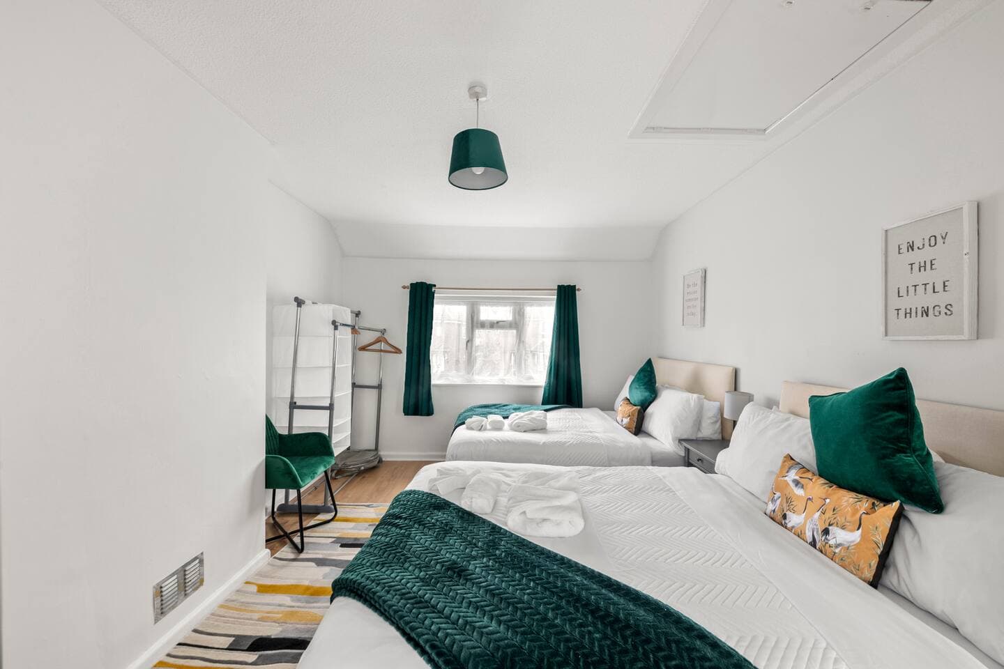 Bedroom in the Reading two-bedroom home with two made-up double beds, green velvet furnishings and a window onto the garden